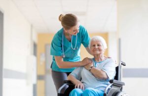 Older LGBTQ+ couple speaking with a compassionate caregiver in a bright assisted living common room.