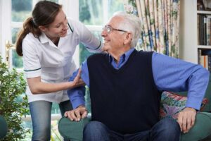 Older adults sharing a quiet conversation at a table in a bright assisted living common room.