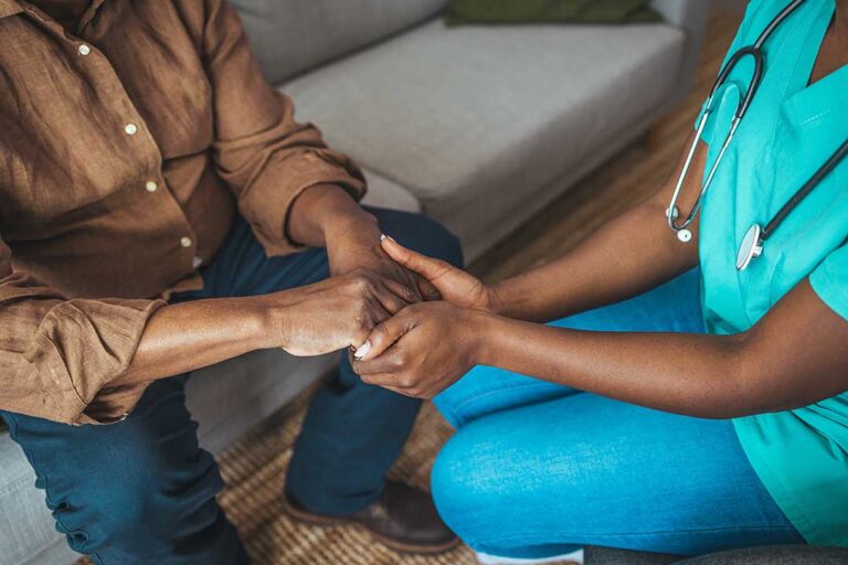 Older adult and caregiver reviewing a medication schedule and daily care plan at a kitchen table.