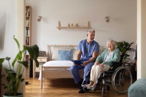 Older adults perform seated and standing exercises with chairs in a bright assisted living activity room.